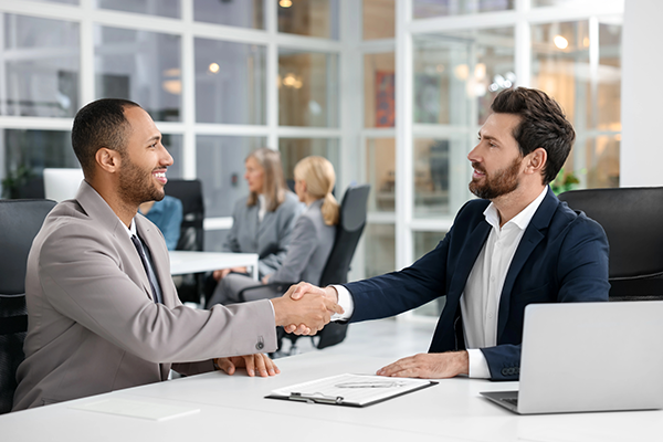 Lawyer shaking hands with client at table in office